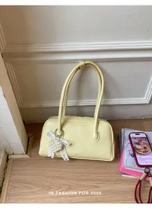 Détail du sac en cuir jaune clair avec pendentif cœur en perles et nœud en dentelle