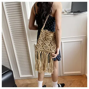 Detail of handcrafted macrame shoulder bag with intricate patterns and long fringe tassels
