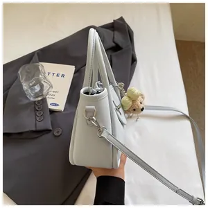 Close-up of light blue litchi pattern bucket bag with silver hardware and plush bear charm