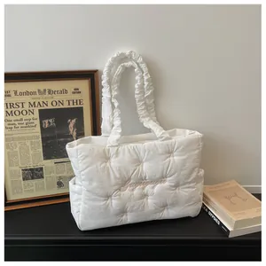 Detail of quilted white tote bag with pink bow embroidery and ruffled edge strap