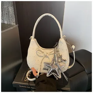 Detail van witte halve maan tas met zilveren sterren en een metalen ballonhond hanger