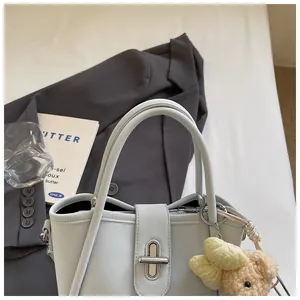 Detail of light blue lychee pattern bucket bag with cute bear charm and metal twist lock