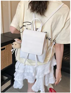 Detailed view of a white PU leather backpack with a plush bear charm and drawstring flap