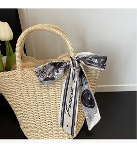 Detail of a beige woven straw tote bag featuring a France print silk ribbon decoration