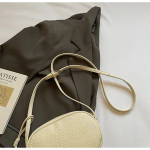 Detail of creamy white pillow bag featuring premium lychee grain leather and precise stitching