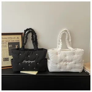 Detail of quilted nylon tote bags with elastic handles and chic bow accents