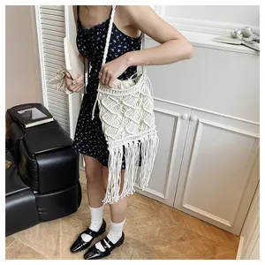 Detailed macro of handmade white macrame bag with tassels and geometric woven patterns