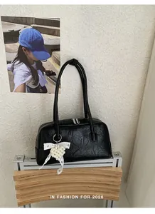 Détail d'un sac à bandoulière en similicuir plissé noir avec nœud en dentelle et pendentif