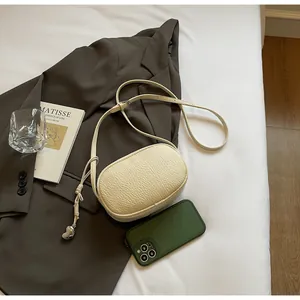Detail of off-white lychee texture bag with silver heart pendant on brown blazer