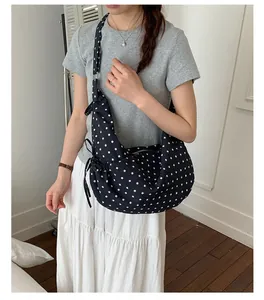 Detailed close-up of black and white polka dot hobo bag with adjustable strap and side bow