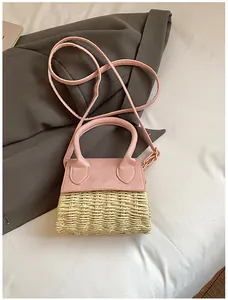 Close-up of pink faux leather and woven straw textures on the mini crossbody bag