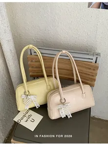 Détail de sacs bandoulière en similicuir avec breloques cœur perlé et nœuds en dentelle