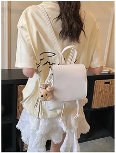 Rear view of model wearing a white PU leather backpack with a cute brown bear pendant