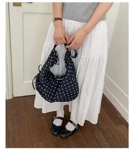 Detail of black polka dot underarm bag featuring a ribbon bow and metal zipper closure