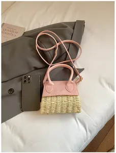 Detail of mini straw handbag with pink leather trim showing texture and top handles