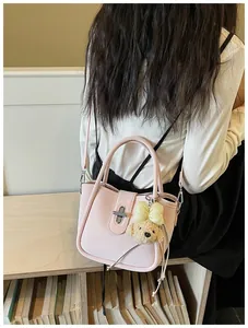 Rear view of a model carrying a light pink lychee textured bucket bag with bear charm