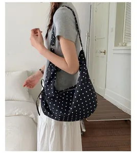 Close-up of a navy blue polka dot crescent shoulder bag with adjustable strap and zip