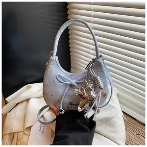 Detail van lichtblauwe hobo-tas met gouden sterren, stoffen strik en zeesterhanger