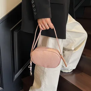Pink lychee leather pillow crossbody bag with silver metal pendant on a model
