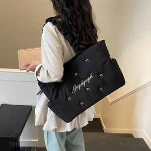 Lightweight black quilted nylon tote bag with ruffled straps and bow embroidery detail