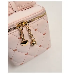 Détails des breloques cœur et sphère dorées sur la fermeture à glissière du sac rose