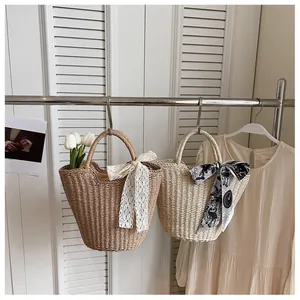 Detail of straw woven tote bags with lace bow and floral scarf hanging on a rack