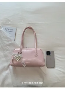 Détail du sac rose avec breloque cœur en perles et nœud en dentelle sur tissu blanc