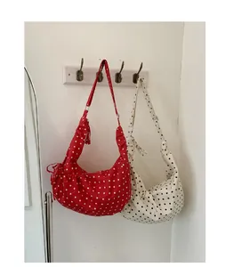 Detail of red and white polka dot half-moon shoulder bags with drawstring accents