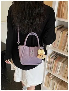 Detail of purple lychee pattern bucket bag with silver twist lock and puppy pendant