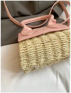 Close-up of the woven straw texture and pink leather strap on a mini crossbody bag
