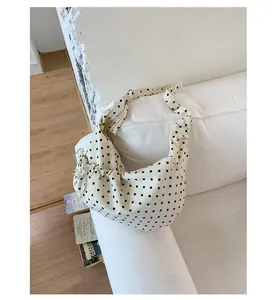 Close-up of beige polka dot canvas bag featuring side drawstring detail on a white sofa