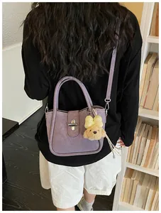 Detail of light purple litchi texture bucket bag with puppy charm and silver twist lock