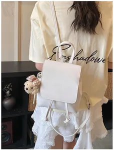 Detailed close-up of a white PU leather backpack with a cute plush bear charm accessory