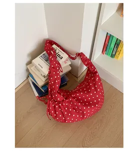 Detailed shot of red polka dot crescent bag with pleated design and metallic zipper