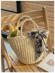 Detail of woven straw tote bag with black and white Paris print silk scarf on handle