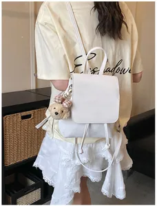 Detail of white mini backpack with drawstring closure and cute plush bear charm
