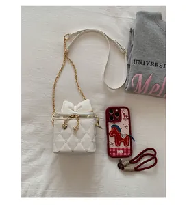 Détails du matelassage en cœur et du nœud sur le mini sac à bandoulière blanc