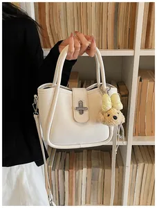 Detail of white lychee textured bucket bag with silver twist lock and cute dog charm
