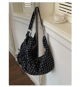 Close-up of black polka dot hobo bag featuring drawstring details and silver metal zipper