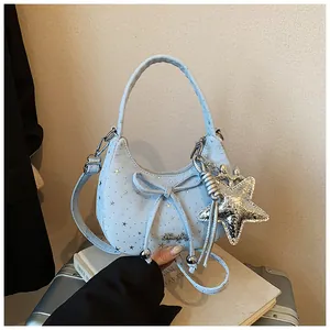 Detail van lichtblauwe tas met strik, zilveren sterrenprint en sterrenhanger
