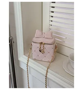 Gros plan d'un mini sac matelassé rose avec broderies de cœurs et breloques dorées