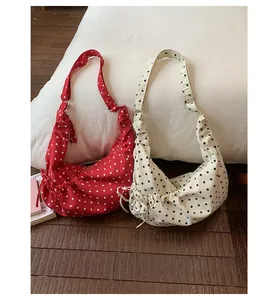 Close-up of drawstring polka dot underarm bags in red and beige on a cozy bed