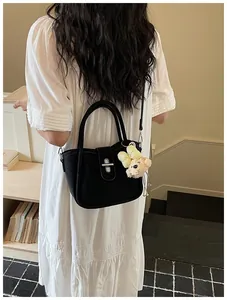 Detail of black lychee texture bucket bag with cute bear charm and silver metal buckle