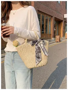 Detail of woven straw tote bag with printed silk scarf and tulip in an outdoor setting