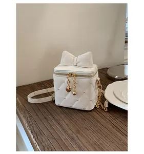 Détail du petit sac blanc matelassé avec nœud décoratif et perles élégantes