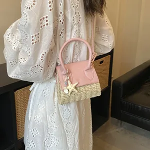 Pink straw woven handbag with starfish pendant for summer fashion, shown on shoulder