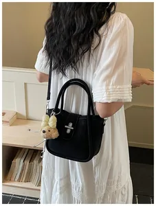 Side view of chic lychee pattern bucket bag with silver twist lock and plush puppy charm