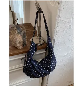 Close-up of navy blue polka dot crescent bag with stylish ruched details and adjustable strap