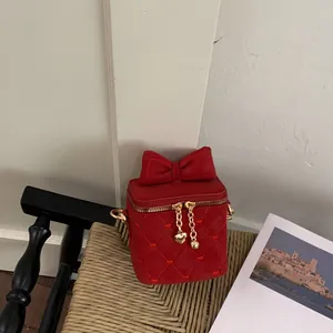 Gros plan sur tissu matelassé rouge avec broderie de cœur et tirettes de zip cœur doré
