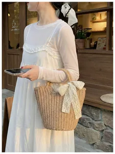 Detail of hand-woven straw tote bag with a large white lace bow in a summer setting